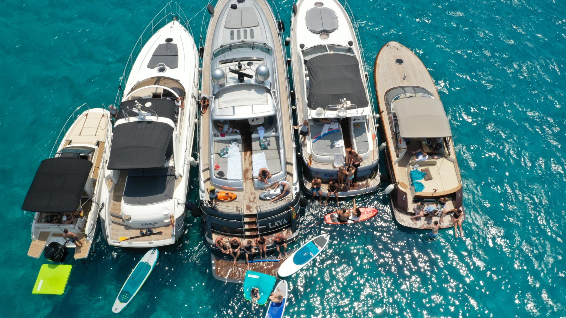 arial shot of five motor yachts moored in a cove for a wedding event boatchartermenorca